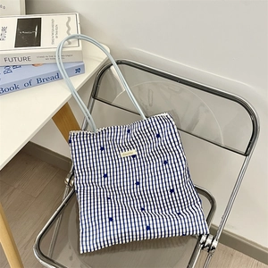 Detail of blue and white checkered canvas tote bag with floral pattern on a chair