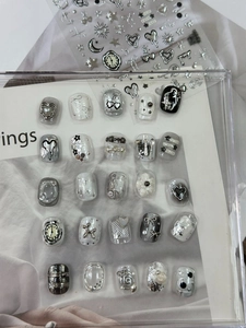 Macro shot of silver metal nail art charms with heart, star, and bow designs