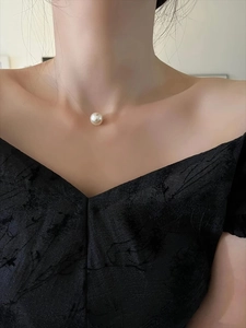 Close-up of a French style pearl pendant on an invisible necklace worn by a model