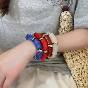 Set of four colorful acetate marble bangles with gold spacers worn in summer casual style