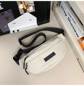 Detail of minimalist cream chest bag with adjustable black strap and premium textured fabric
