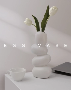 Detail of white pebble ceramic egg vase with minimalist stacked design and tulips