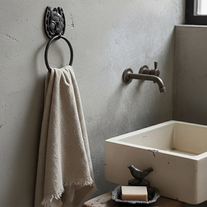 Industrial horseshoe towel rack with horse head relief and ring on a concrete wall