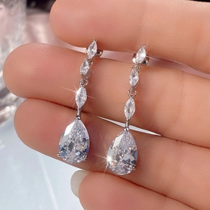 Silver marquise and pear-cut cubic zirconia drop earrings held in hand for bridal jewelry