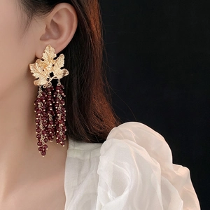 Vintage gold leaf tassel earrings with deep red beads shown on a model side profile