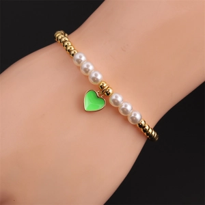 Elastic gold bead and pearl bracelet featuring a vibrant green heart enamel pendant