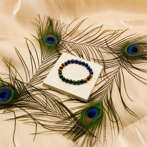 Close-up of a 10mm tiger eye and malachite stretch bracelet on silk with peacock feathers