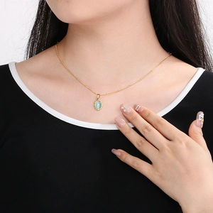 Close-up of a vintage oval opal pendant on a gold beaded stainless steel necklace