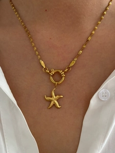 Macro detail of gold starfish pendant on twisted rope chain necklace worn by a model