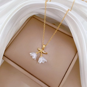 Elegant gold lily of the valley necklace with white flowers and crystals on silk fabric