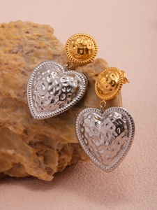 Detail of gold and silver heart drop earrings with a hammered metal texture finish