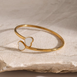 Detail of 18k gold heart-shaped bangle featuring elegant white enamel inlay on stone