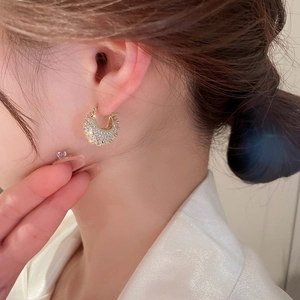 Close-up of gold-plated C-shaped hoop earrings with pave-set cubic zirconia on ear