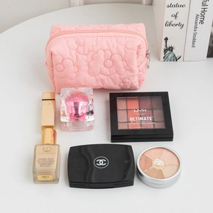 Macro shot of pink quilted floral makeup bag holding high-end cosmetic essentials