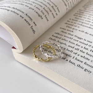 Irregular textured S925 sterling silver rings in gold and silver finish on a book