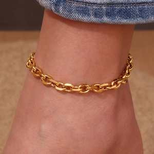 Detail view of a chunky gold box chain anklet made of titanium steel on an ankle