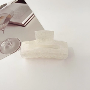 Close-up of translucent white square hair claw with shimmering glitter and star-like finish