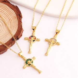 Detailed view of three 18K gold plated cross pendants with inlaid green and clear zircons
