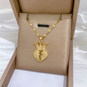Golden crown heart pendant necklace with shimmering crystals on white silk background