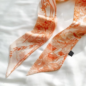 Detail of a thin polyester scarf with classical orange art prints and washing label