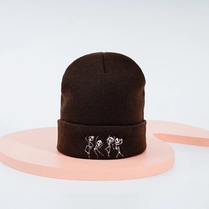 Détail de la broderie squelette dansant sur un bonnet en maille marron foncé