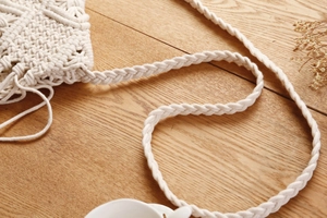 Nahaufnahme von handgefertigtem weißem Baumwoll-Macramé-Muster und geflochtenem Gurt