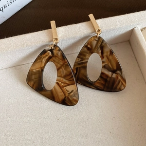 Close-up of geometric resin leopard print earrings with gold metal accents on a tray