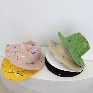 Macro detail of various color straw hats featuring artistic colorful splatter paint design