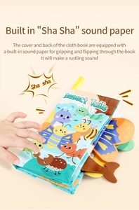Close-up of baby hand touching 3D insect tails on crinkle cloth book for sensory play