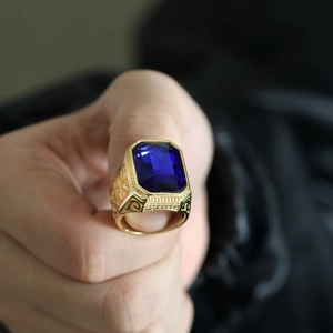 Macro shot of gold stainless steel ring featuring a large emerald-cut deep blue gemstone