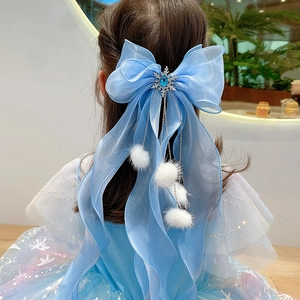 Close-up of blue bow hair clip with snowflake gem and white fur ball tassels on model