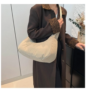 Quilted beige crescent bag worn over a leopard print coat for a stylish winter look