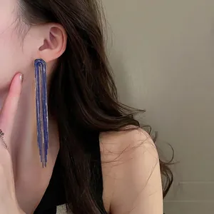 Elegant U-shaped long tassel drop earrings in blue and gold on female model