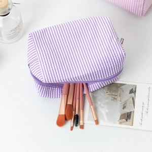 Close-up of seersucker striped makeup bag in purple with makeup brushes inside
