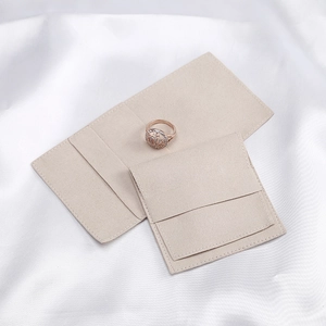 Detail of beige velvet jewelry envelope pouches in two sizes on silk background