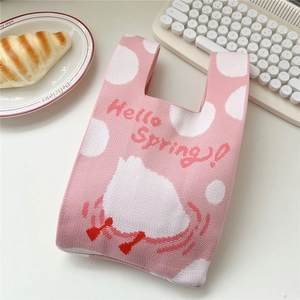 Detail view of a pink knit handbag with Hello Spring pattern and bunny design