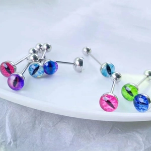 Set of seven colorful eye-patterned stainless steel tongue rings displayed on a white plate