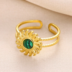 Macro view of gold sunburst ring featuring a green stone inlay and textured band