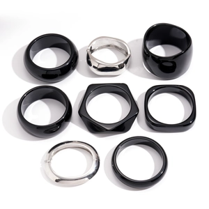 Set of minimalist black resin and polished silver geometric bangles on white background