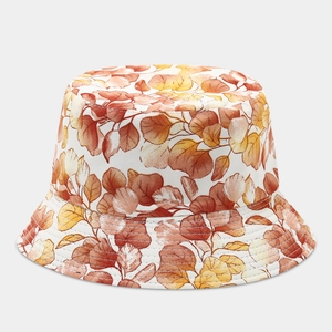Detail of canvas bucket hat featuring warm autumn leaf patterns in orange and yellow tones