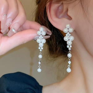 Close-up of elegant long tassel earrings with white pearls and sparkling rhinestones