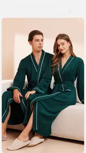 Detail of dark green cotton bathrobes with white piping and belted waist for couples