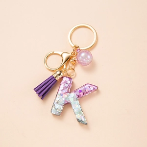 Resin letter K keychain with purple glitter, silk tassel and gold alloy clasp on light beige