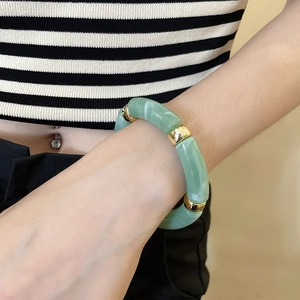 Detailed close-up of iridescent acrylic bead bracelet with polished gold spacers on wrist