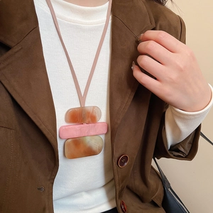 Detailed view of the layered acrylic square pendant necklace on a cozy sweater