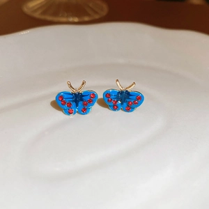 Close-up of blue butterfly studs with red crystals and golden metal accents