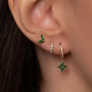 Macro detail of gold-plated earring set featuring green marquise stones and zircon pavé
