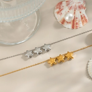 Elegant gold and silver star necklaces displayed with shells and pearls on beige background
