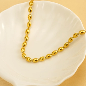 Minimalist gold bead necklace with brushed metal oval beads displayed on a white shell plate