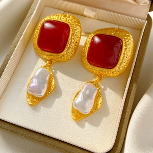 Detailed macro of vintage earrings with red resin stones and baroque pearls in a jewelry box